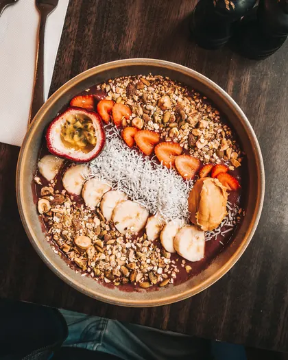 Acai bowl topped with banana, strawberries, passionfruit, granola and coconut