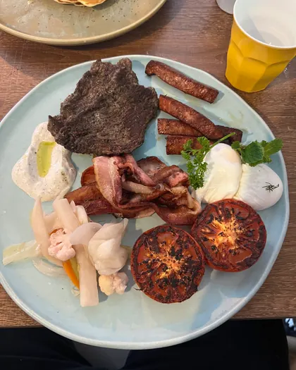 A big breakfast plate with steak, bacon, sausage, hash browns and poached eggs