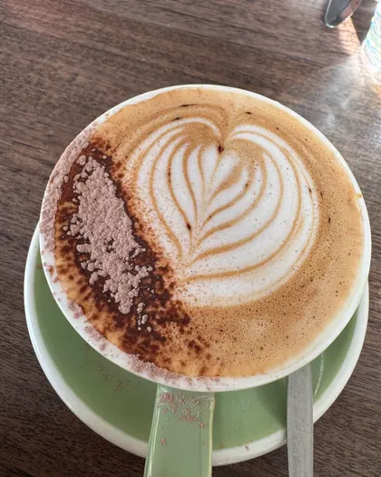 A cappuccino with latte art in a sage green cup